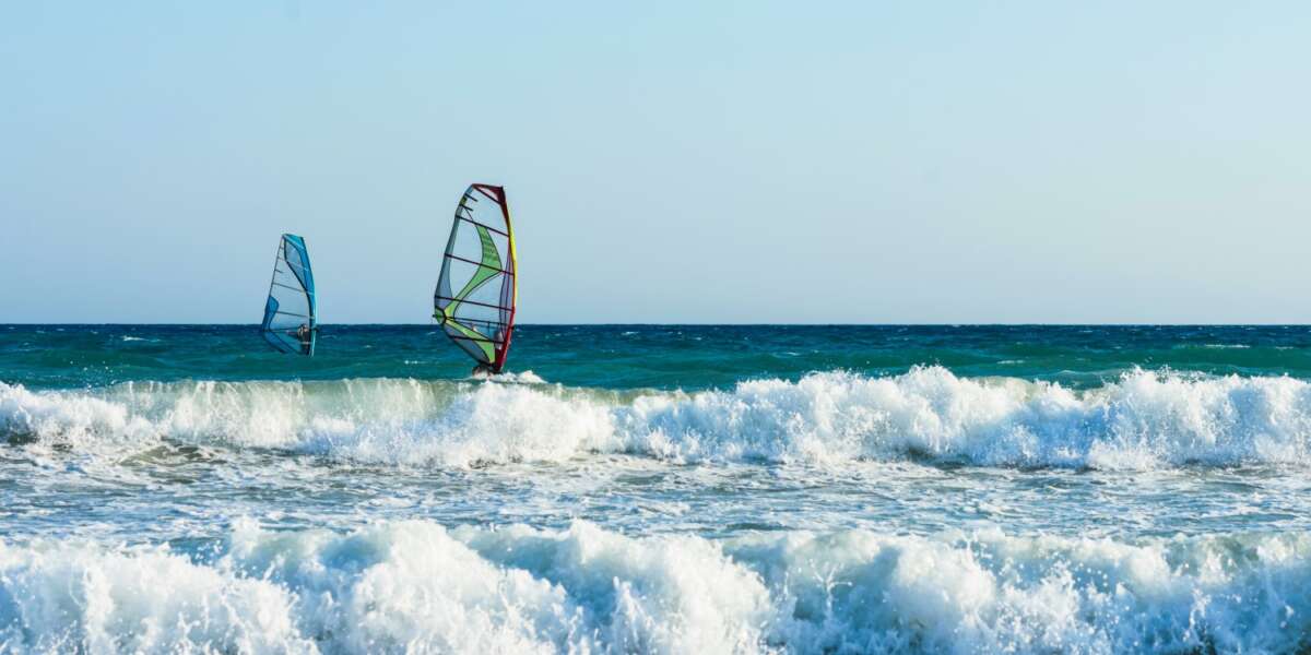 Windsurfers in the sea on Crete on sunset. Windsurfing in Heraklion